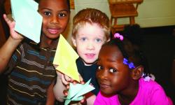Three children hold up their paper animal creations.